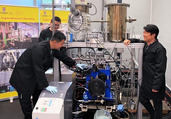 Výskumníci z UNSW profesor Shawn Kook (vpravo), Xinyu Liu (vzadu vľavo) a Jinxin Yang (vpredu vľavo) s testovacím zariadením na modernizáciu dieselového motora na vodíkový.
