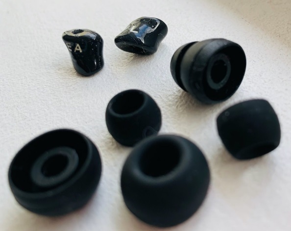 Prispôsobené špičky slúchadiel do uší Ambeo (vzadu) v porovnaní so štandarndými silikóonovými špičkami z bežných slúchadiel do uší.