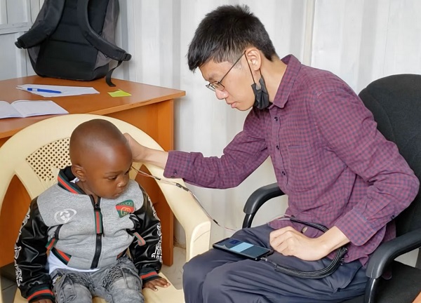 Vedúci výskumník Justin Chan používa zariadenie na testovanie sluchu dieťaťa.