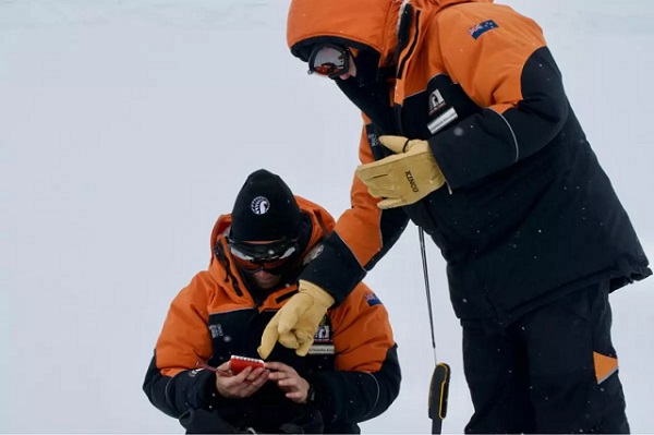 Výskumníci zaznamenávajú údaje o mieste odberu vzoriek snehu v Antarktíde.