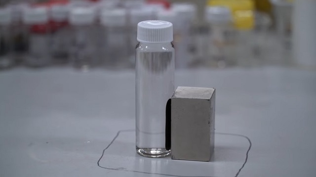 Vzorka kontaminovanej vody upravenej pomocou novej techniky, pričom chemikálie PFAS sú priťahované na stranu s magnetom.