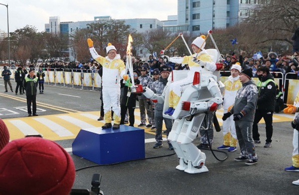 Profesor Jun-ho predal plameň ďalej Jung Jae Leeovi, členovi víťazného tímu Samsung Junior Software Cup, ktorý sa viezol na špeciálnej robotickej stoličke s pohonom v dvoch nohách s názvom FX-2.