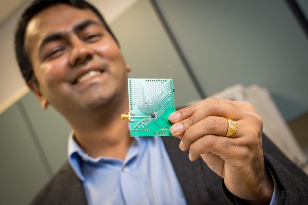 Profesor Dinesh Bharadia drží dosku s plošnými spojmi, na ktorej je osadený aj miniatúrný Wi-Fi čip.