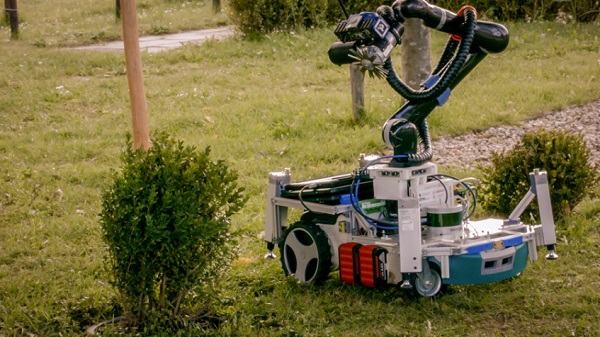 Robotický záhradník Trimbot orezáva krík.